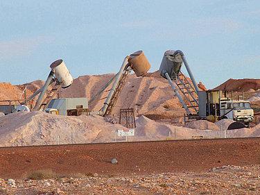 Blick auf eine Opalmine im Tagebau, in der mit schwerem Gerät nach Opal gesucht wird.