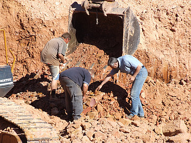 Nahaufnahme von drei Minenarbeitern, die bei einer Boulderopal-Mine nach Opalen suchen.